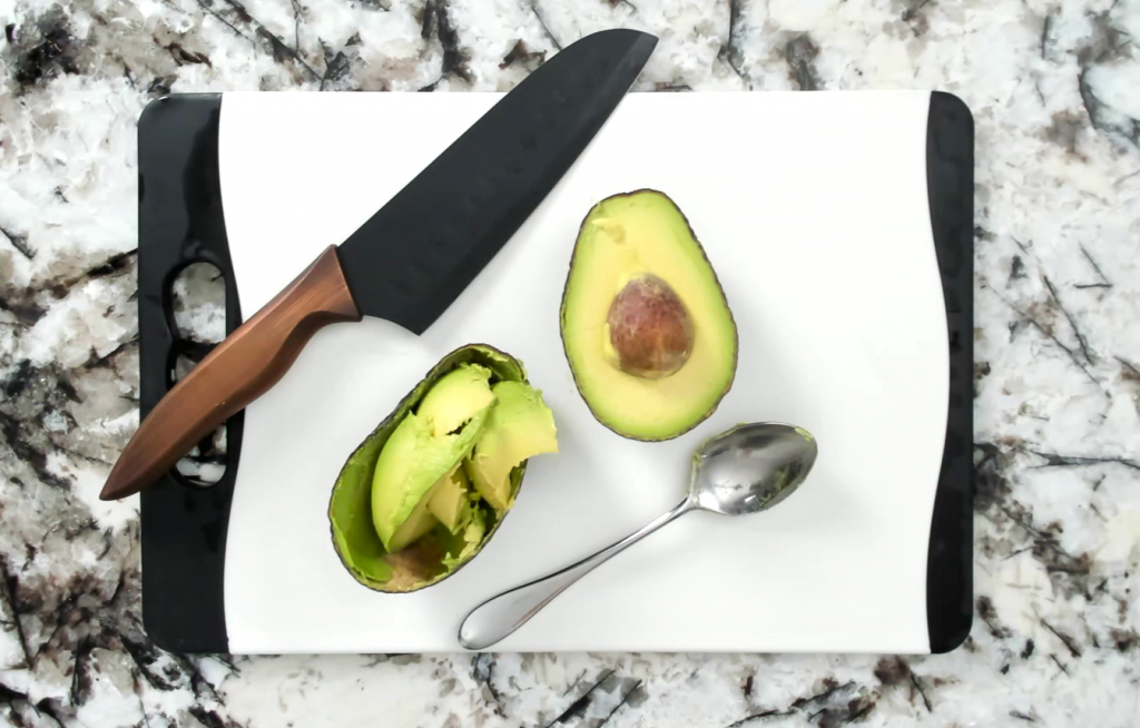 cut up avocado and knife and spoon on a cutting board